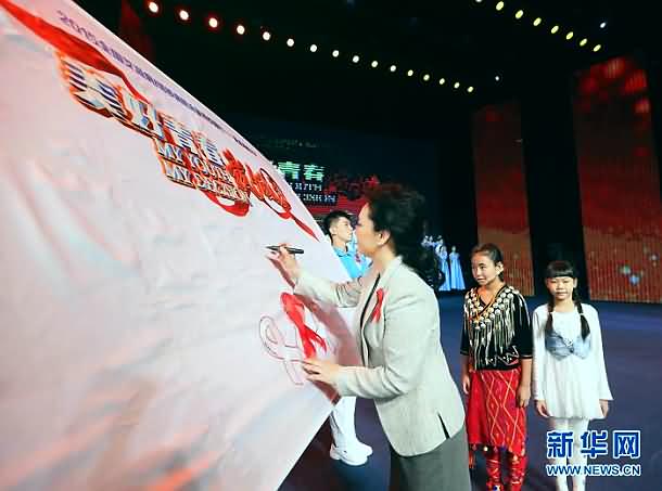彭丽媛把象征反歧视的红丝带装点在艾滋病/结核病防治宣传校园行旗帜上签字